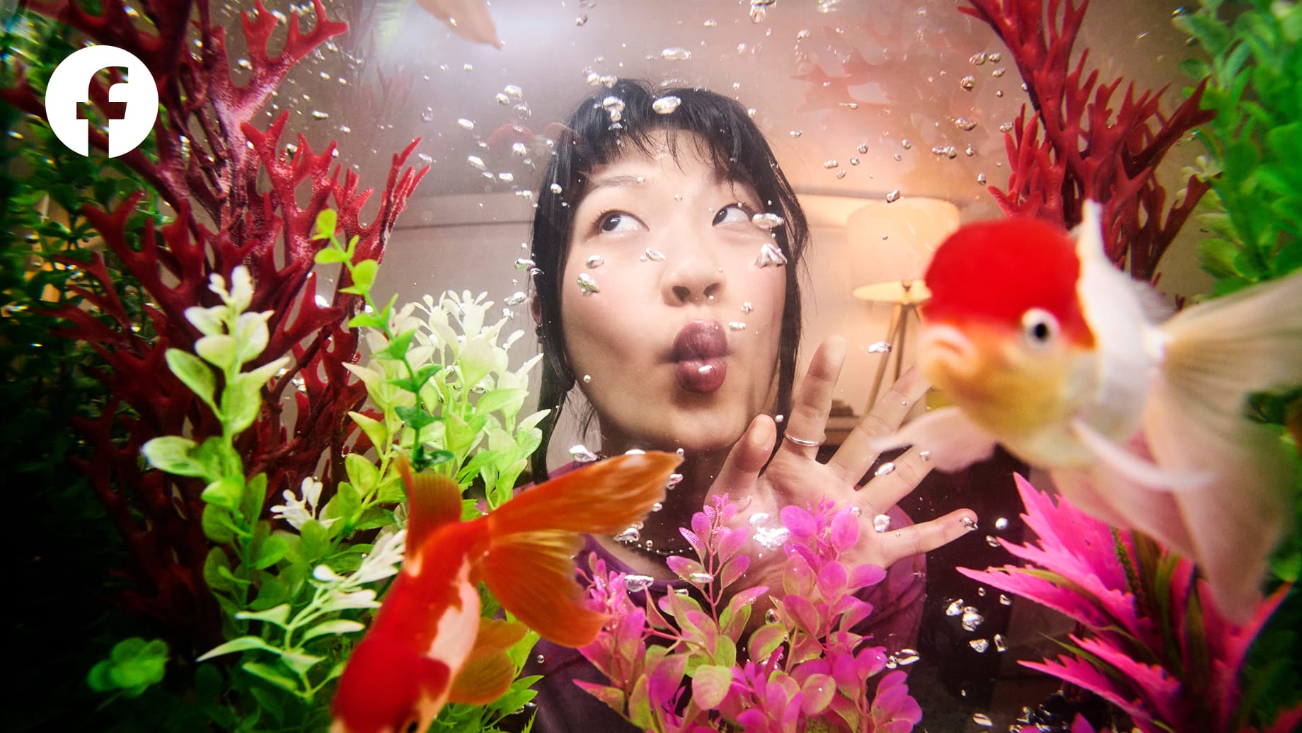 Photo shot through a fish tank, a person making a fish face