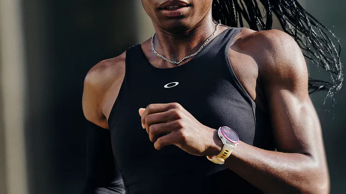 Woman running in a black Oakley branded vest with a white Garmin watch on her left wrist