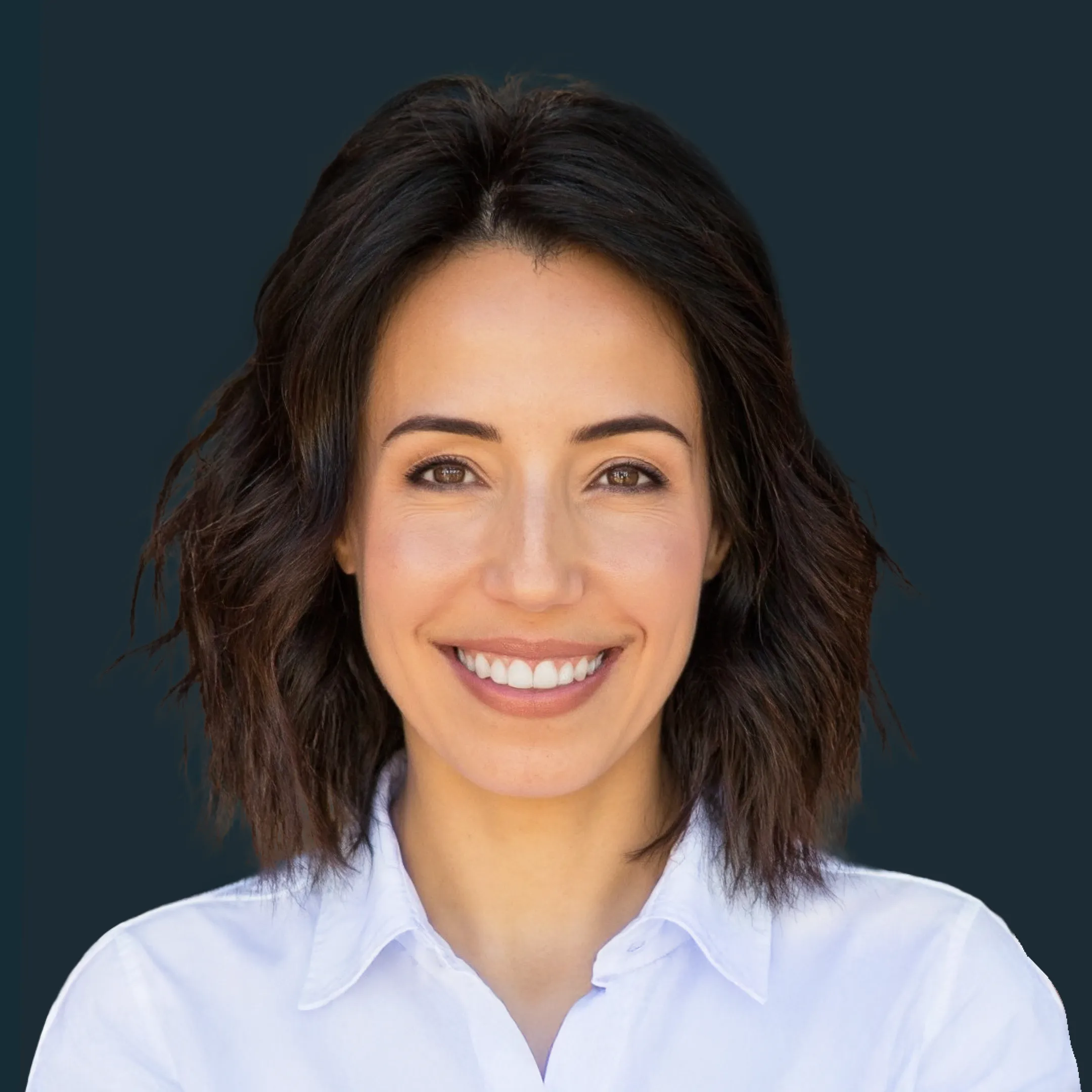 A woman with short brown hair wearing a white button-up shirt smiles against a dark background.