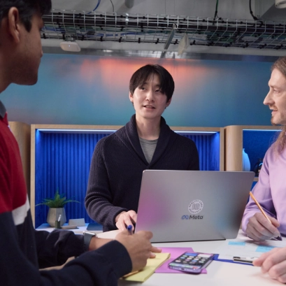 A man at a conference table with a laptop, discussing in a meeting.