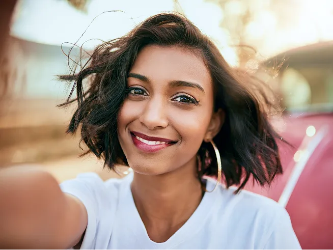Un jeune sourit en prenant un égoportrait par une journée ensoleillée.
