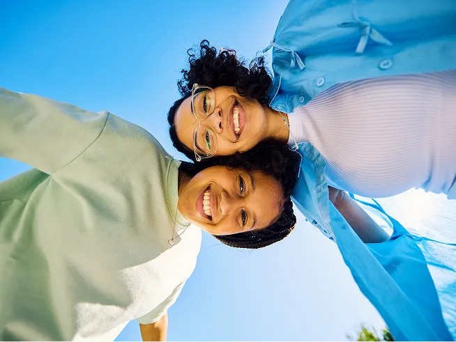Two teens standing across from each other look down at a camera pointed straight up from the ground.