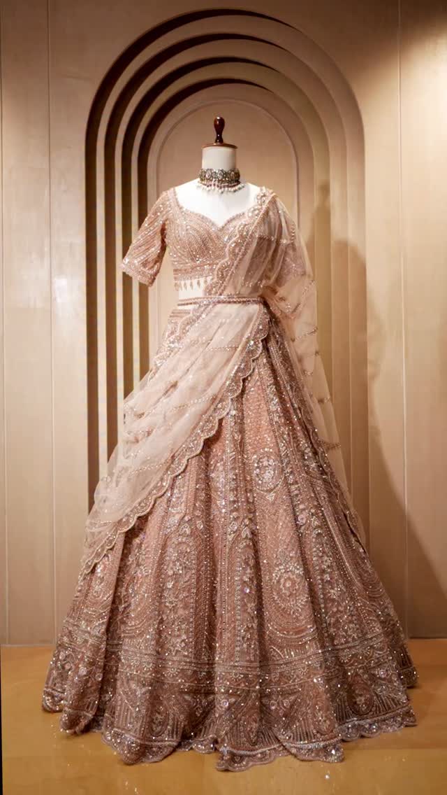 rose gold indian wedding dress This is an exquisite champagne-gold lehenga choli featuring intricate silver zardosi and sequin embroidery. The ensemble includes a structured blouse with a sweetheart neckline and a voluminous, style:Maxi