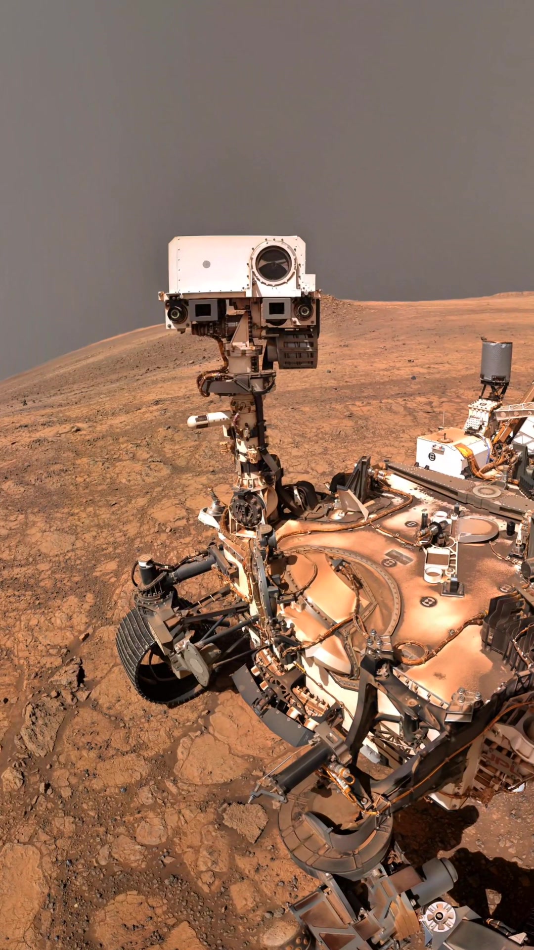 A robotic rover travels across the dusty surface of Mars, studying ...