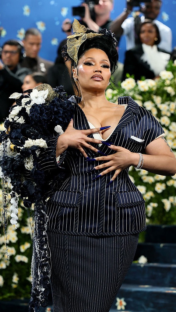 After 8 iconic #MetGala appearances, #NickiMinaj did not disappoint, stepping out in a chic pinstripe suit-dress, her hair piled high in a curly updo, and topped off with a stunning gold headpiece. 