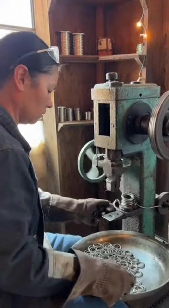 Woman Sitting Next to Machine Producing Metal Rings Discover the skill ...