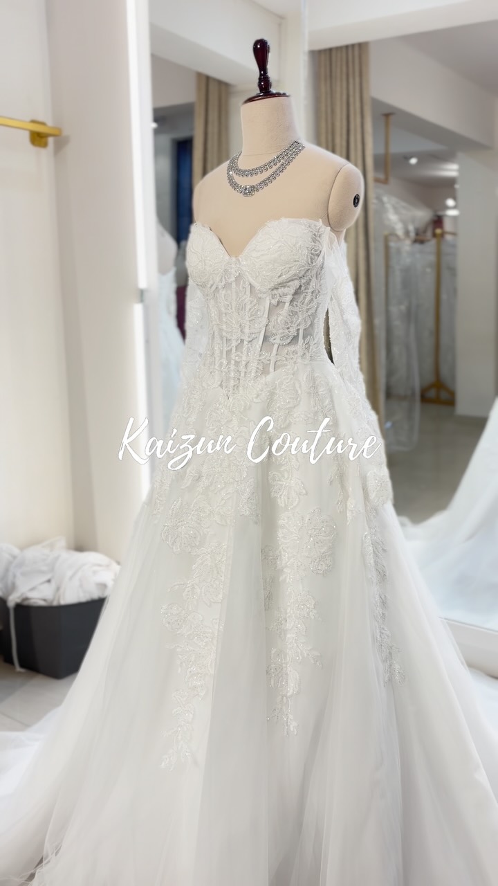 A unique lace beauty featuring an A line silhouette, a basque waist, exposed corset and beautiful beaded lace over a tulle skirt. Perfect for the Modern Kaizun Bride 👰‍♀️. , Shop our latest 