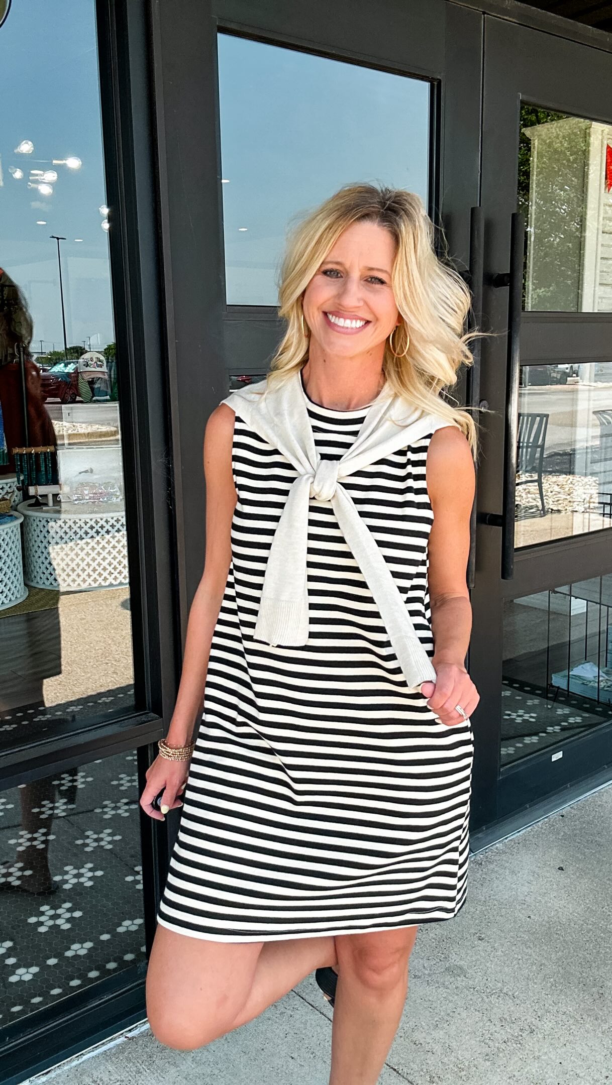 A classic with a cozy twist. 🖤 This cream and black striped sleeveless dress features the cutest faux sweater draped over the shoulders for a layered look—without the extra bulk! It’s effortlessly 