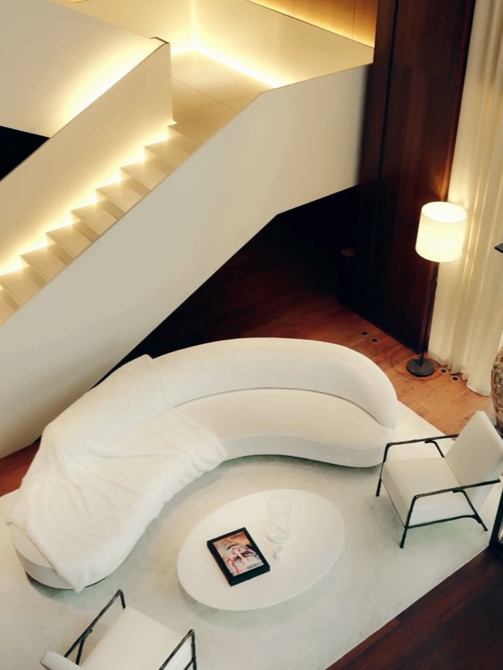 The ivory sofa, draped in soft white faux fur, invites you to