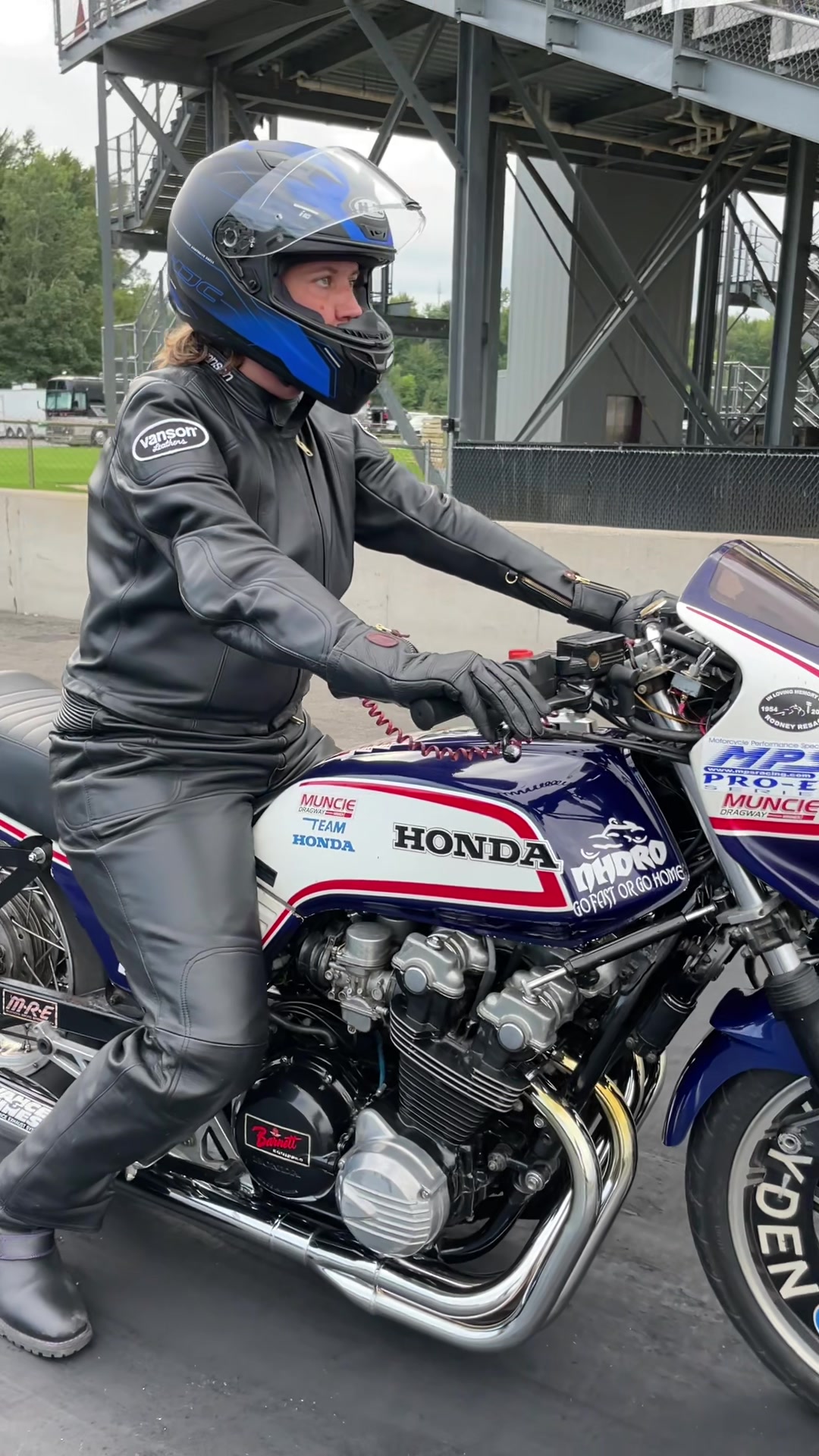 Woman waiting by old Honda motorcycle on residential street