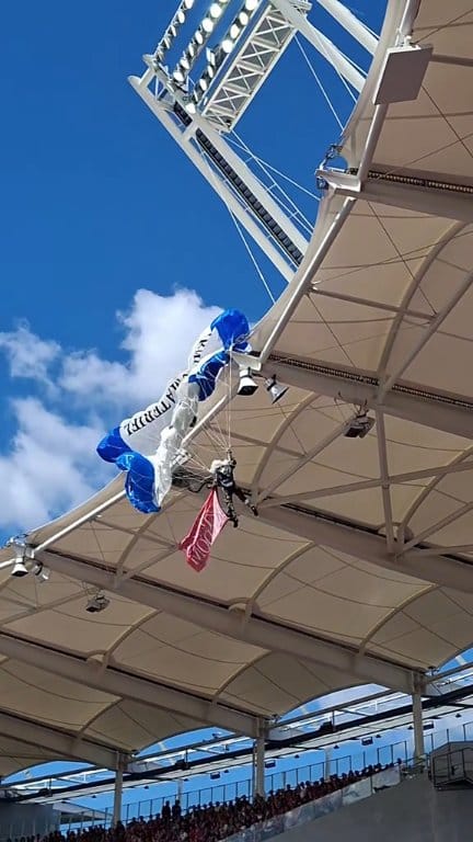 Suspended in mid-air on the roof of the stadium, this parachutist was ...