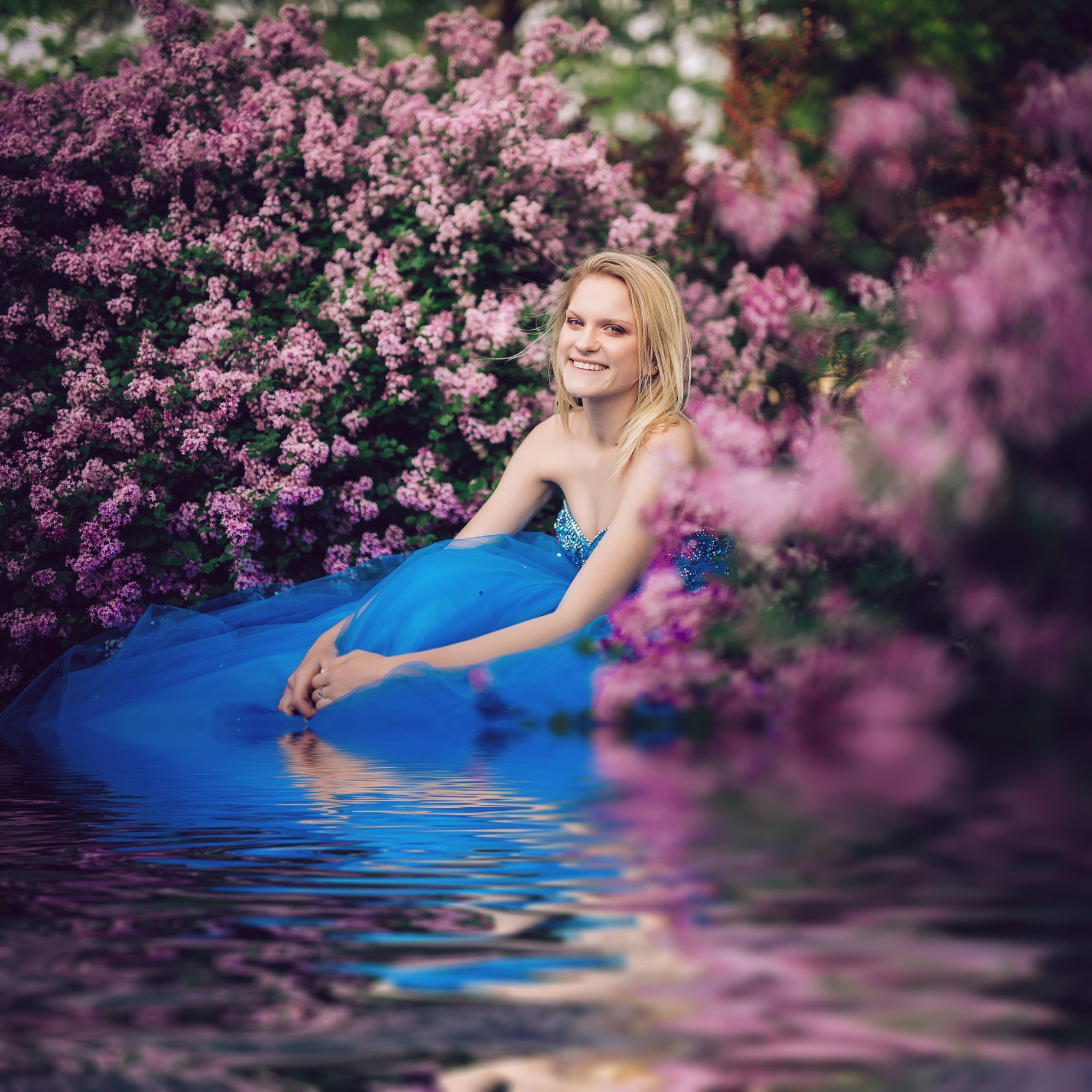 A lady in a blue dress surrounded by vibrant flowers