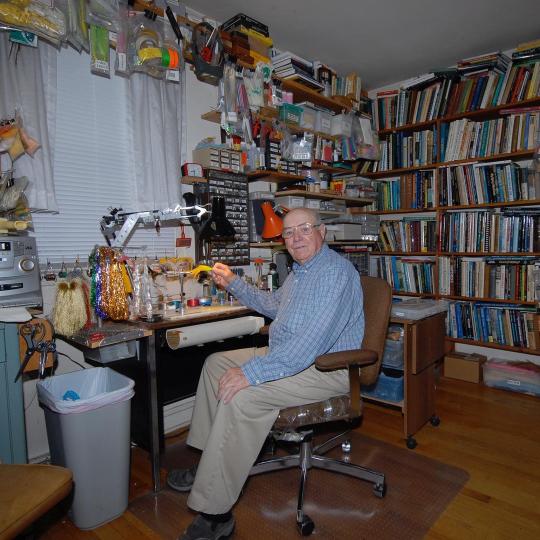 American - Lefty Kreh sits at his tying desk in Maryland holding one of ...