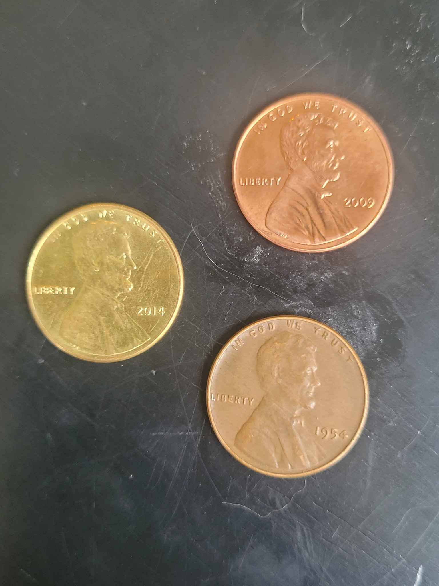 The penny on the left has a gold tone to it. It weighs 2.51 grams 