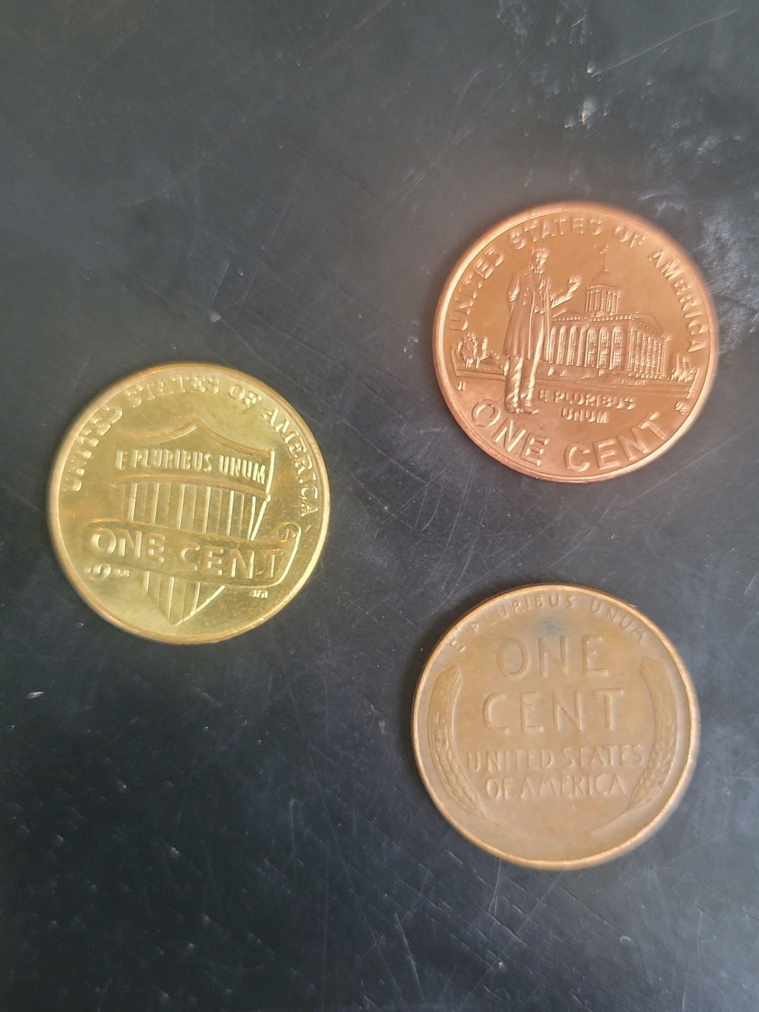 The penny on the left has a gold tone to it. It weighs 2.51 grams 