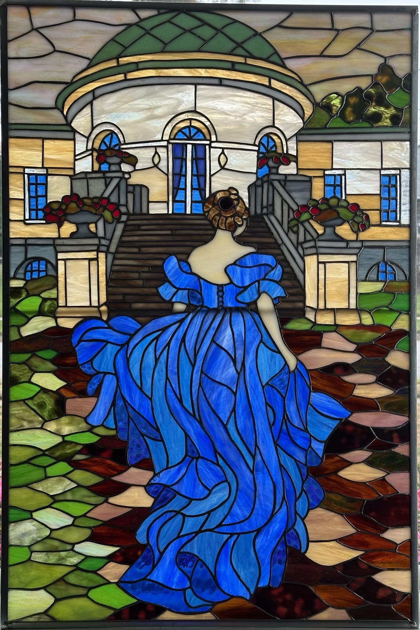 Stained glass artwork of a woman in blue dress near completion