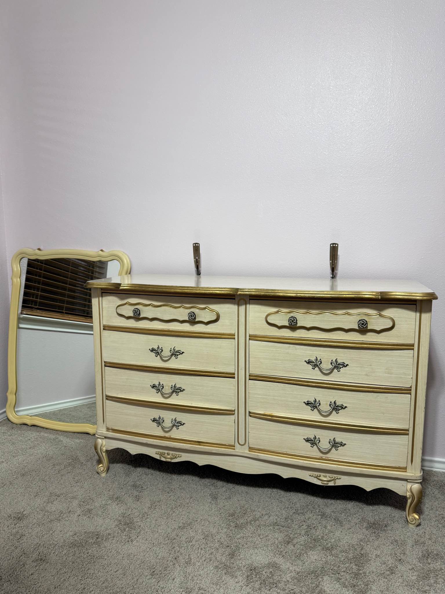 Vintage French Provincial style six-drawer double dresser with an ivory finish and gold-gilded trim, accompanied by a matching wall mirror. Purchased in 1973