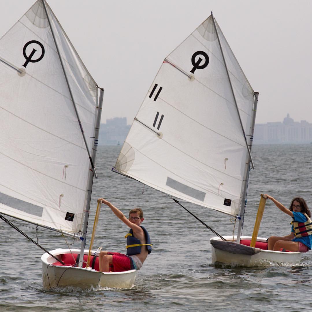 Manhattan - Opti sailors raising their centerboards as they sail ...