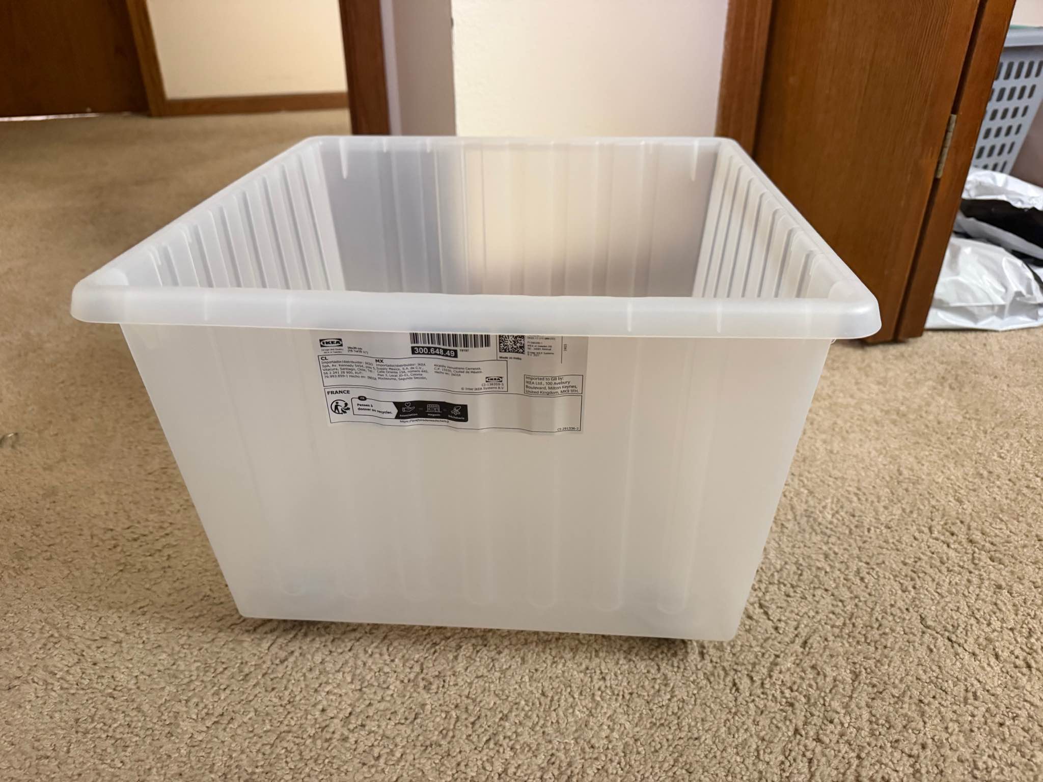 Versatile plastic storage crate is a translucent white IKEA VESSLA model. It has four grey casters on the bottom for mobility. The crate is 39x39 cm