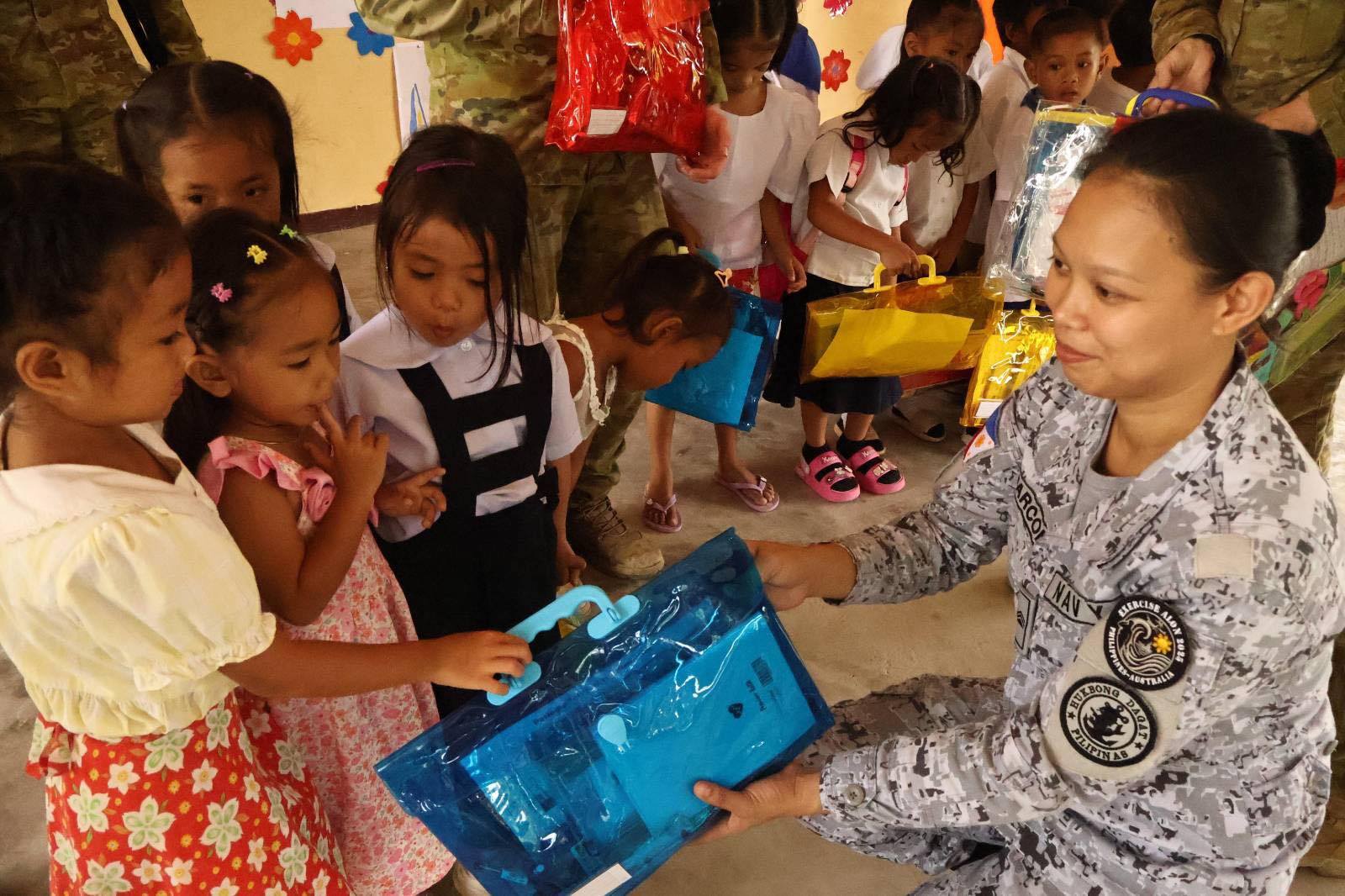 Armed - A Filipina Navy soldier from the AFP hands out school supplies ...