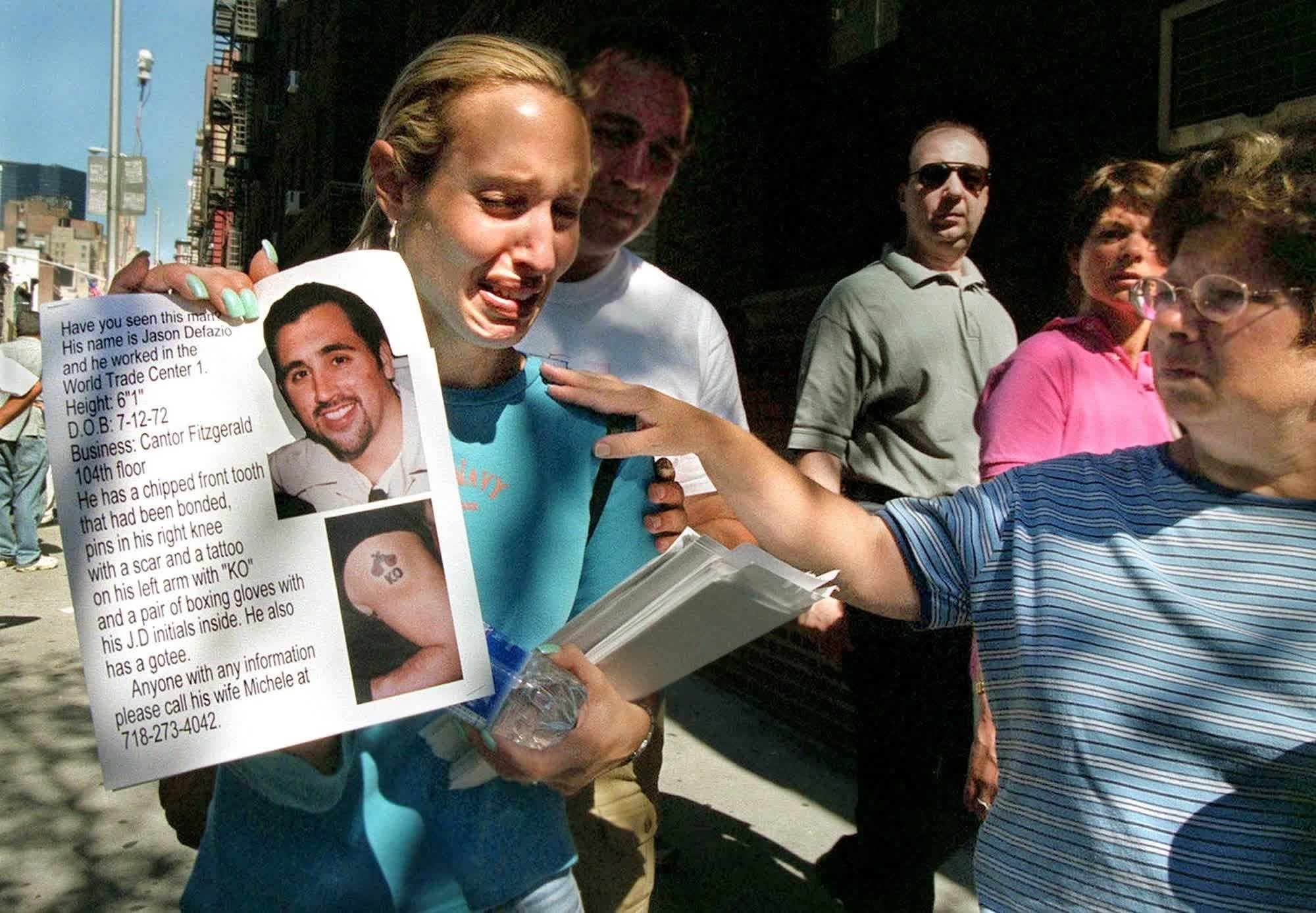 In - Days after the attacks, Michele DeFazio holds up a poster of her ...