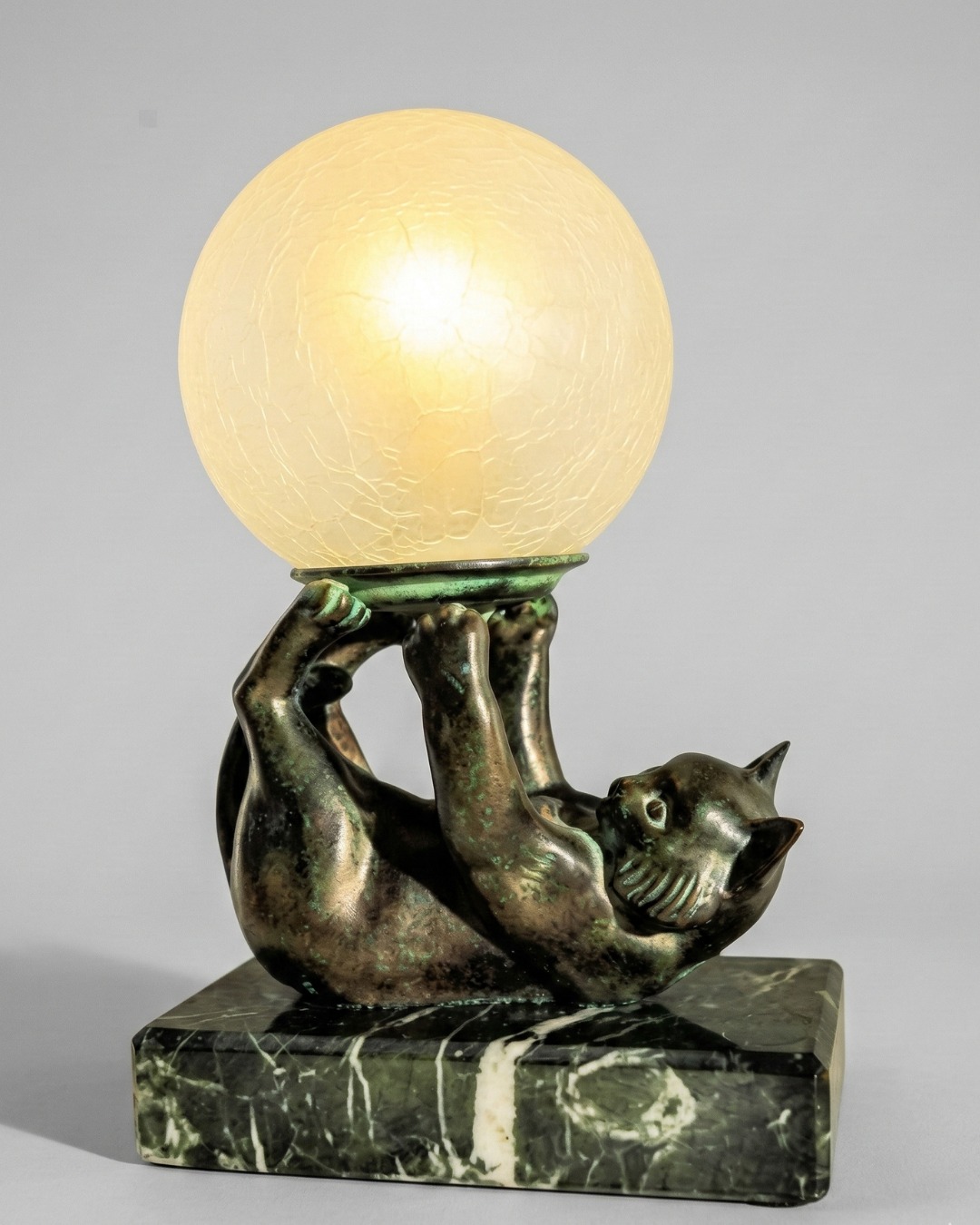 A captivating blend of bronze, marble, and glass, this 1920 cat