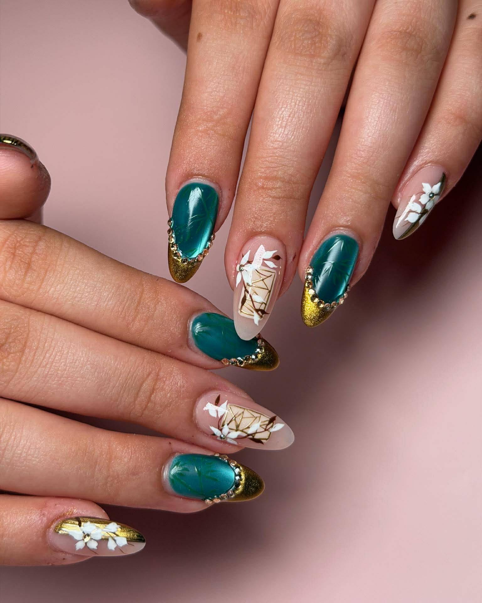 Luxurious emerald green nail design with gold tips and rhinestones