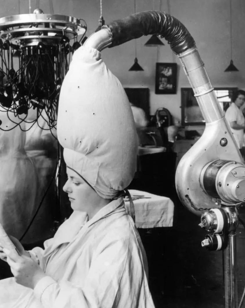 Historical - A woman sits beneath an early blow-drying machine in 1937 ...