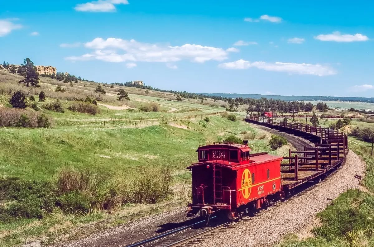 LIVE - A Santa Fe caboose punctuates a string of empty CWR cars leaving ...