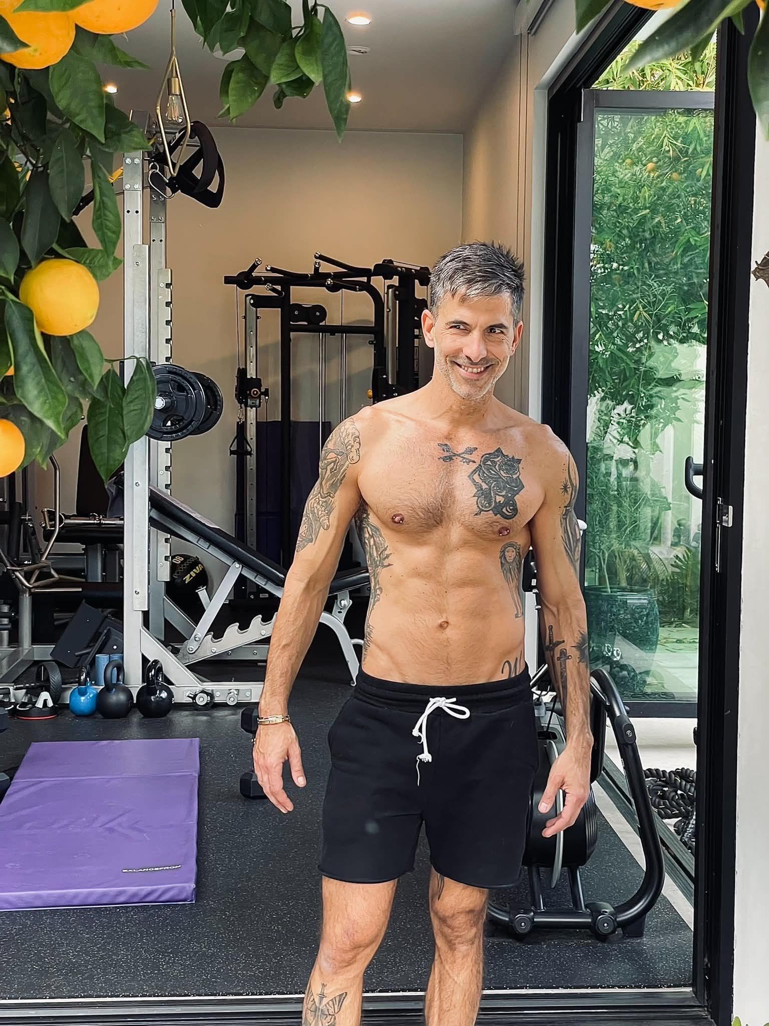 Shirtless tattooed man in home gym