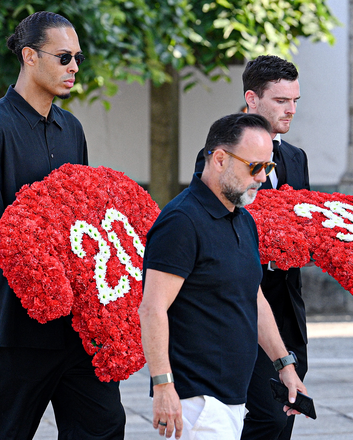 Virgil van Dijk and Andy Robertson holding floral tributes at 