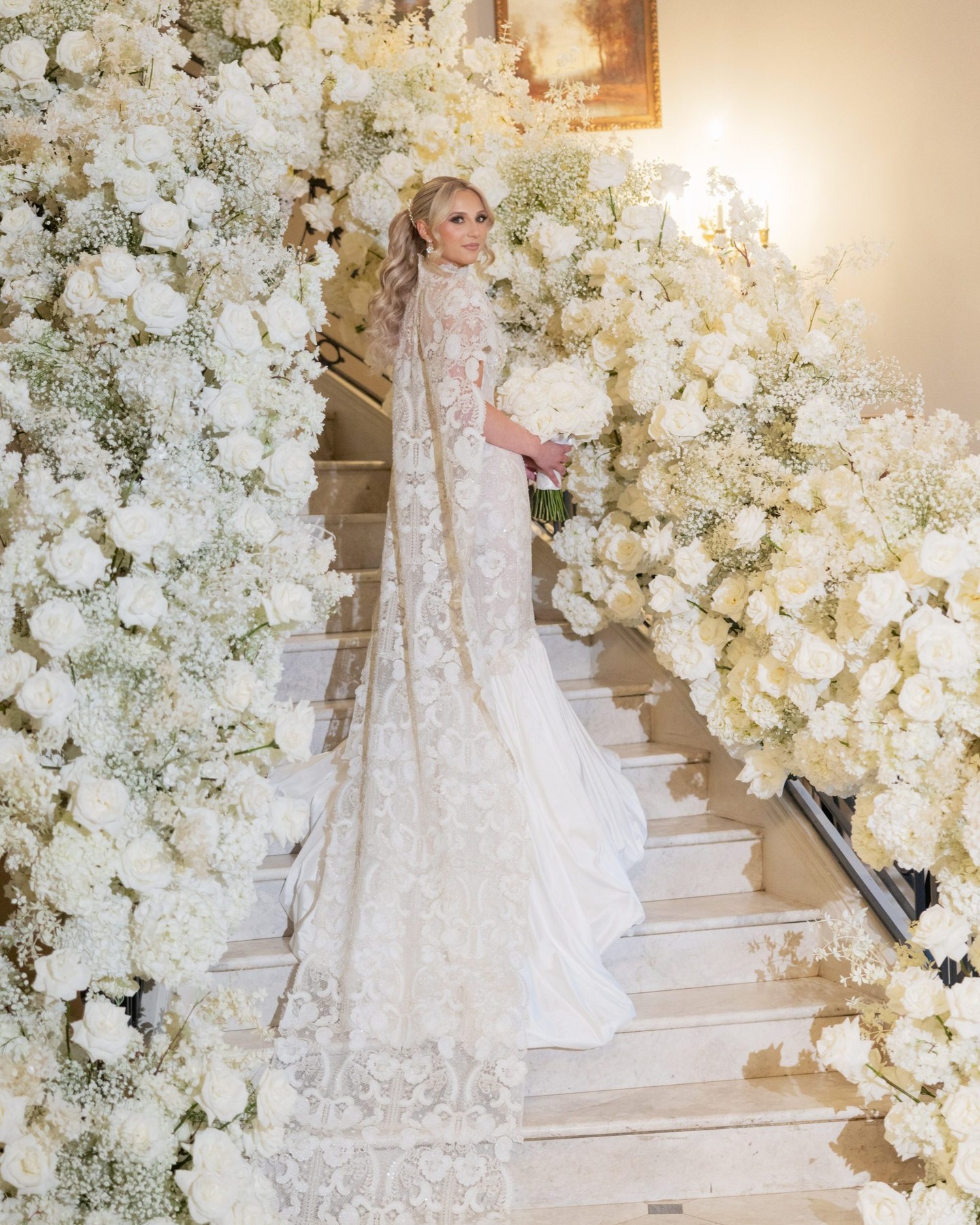 Amaya' by Kim Kassas Couture, a striking mermaid silhouette crafted from silver and ivory Indian embroidered lace. Intricate 3D floral embroidery adorns the bodice, softly mimicking pearls, while the dramatic balloon mermaid