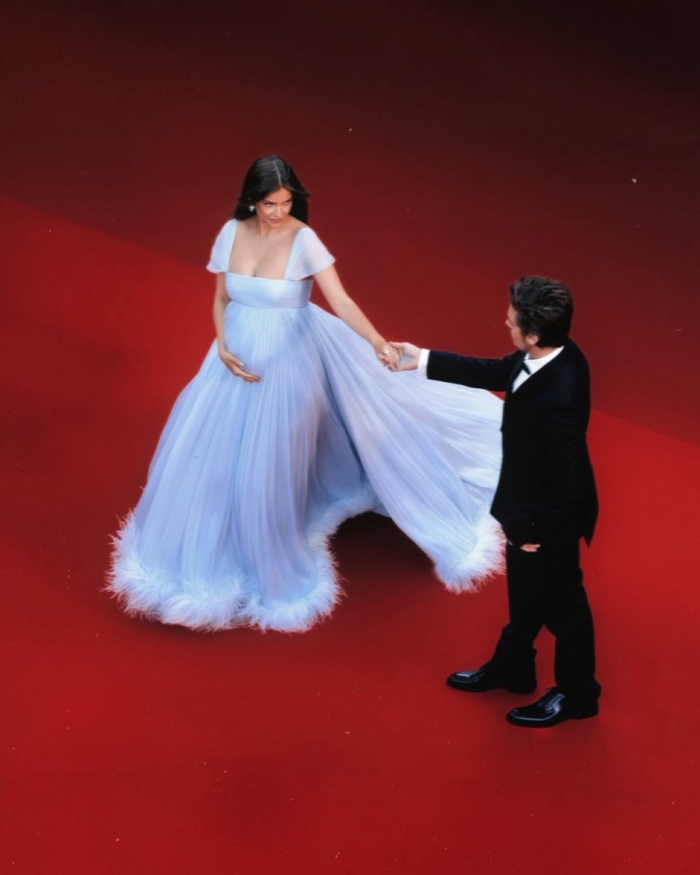 Barbara Palvin revealed her pregnancy at Cannes in a custom baby blue Miu Miu gown, arriving with Dylan Sprouse in a Cinderella-like red carpet moment made for the reveal. The soft empire
