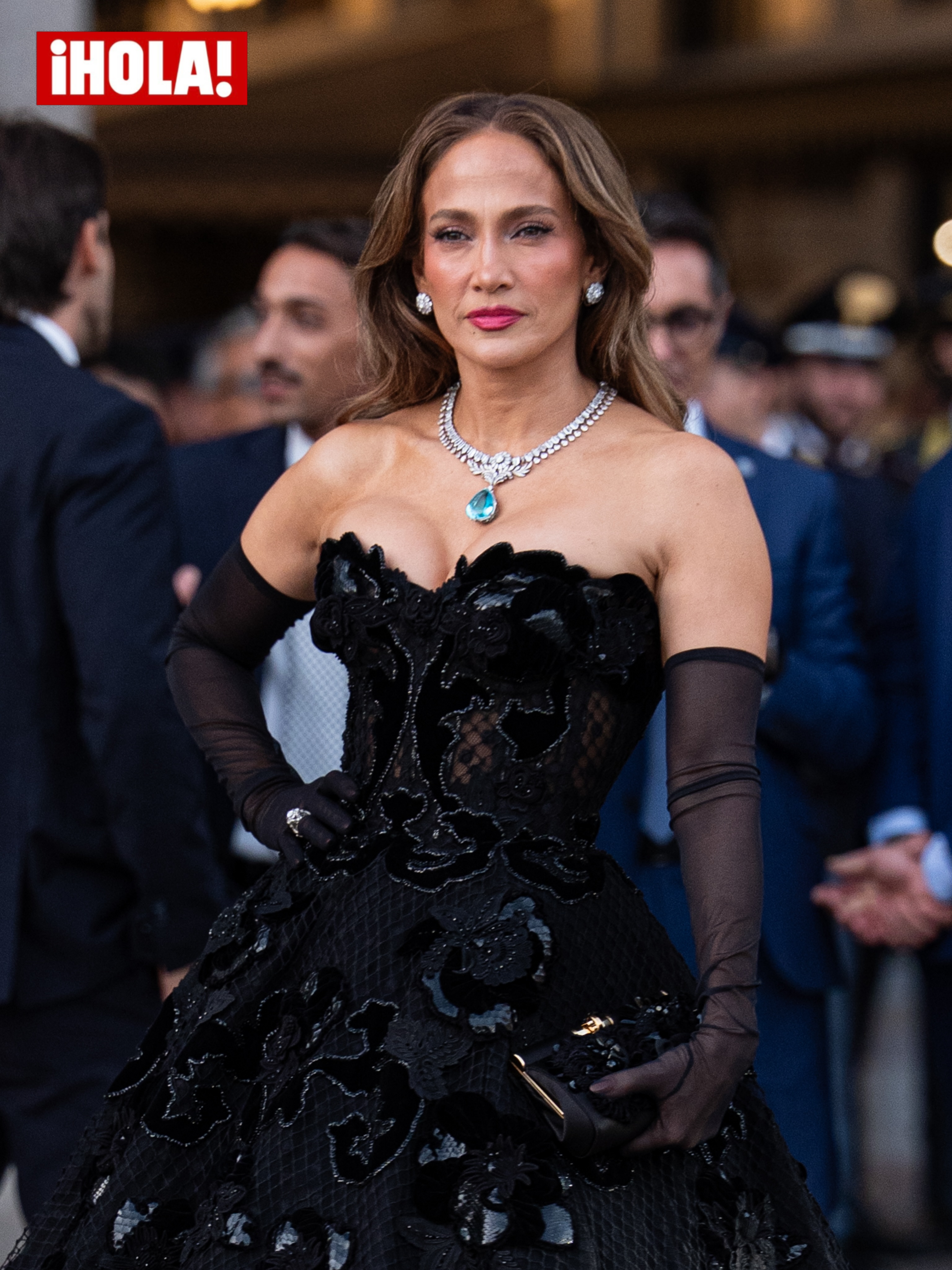 Jennifer Lopez made a dramatic entrance at Milan Fashion Week, commanding attention in a sculptural black gown with intricate floral embellishments, sheer opera gloves and striking turquoise jewelry