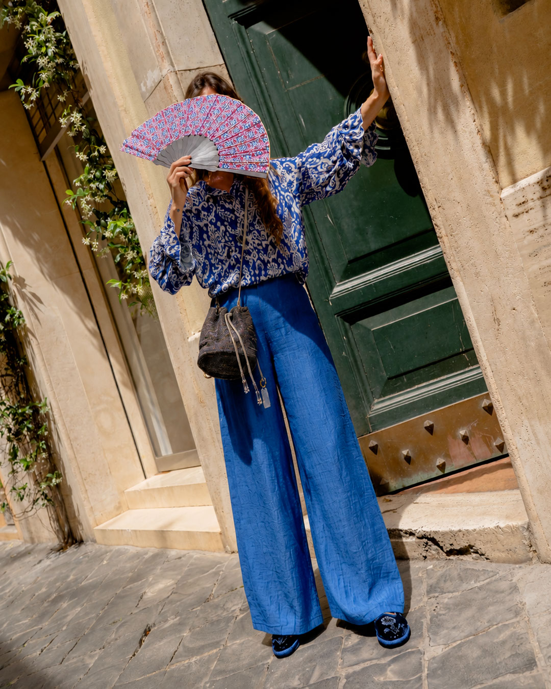 Amid ancient doors and Mediterranean light, an intense blue look