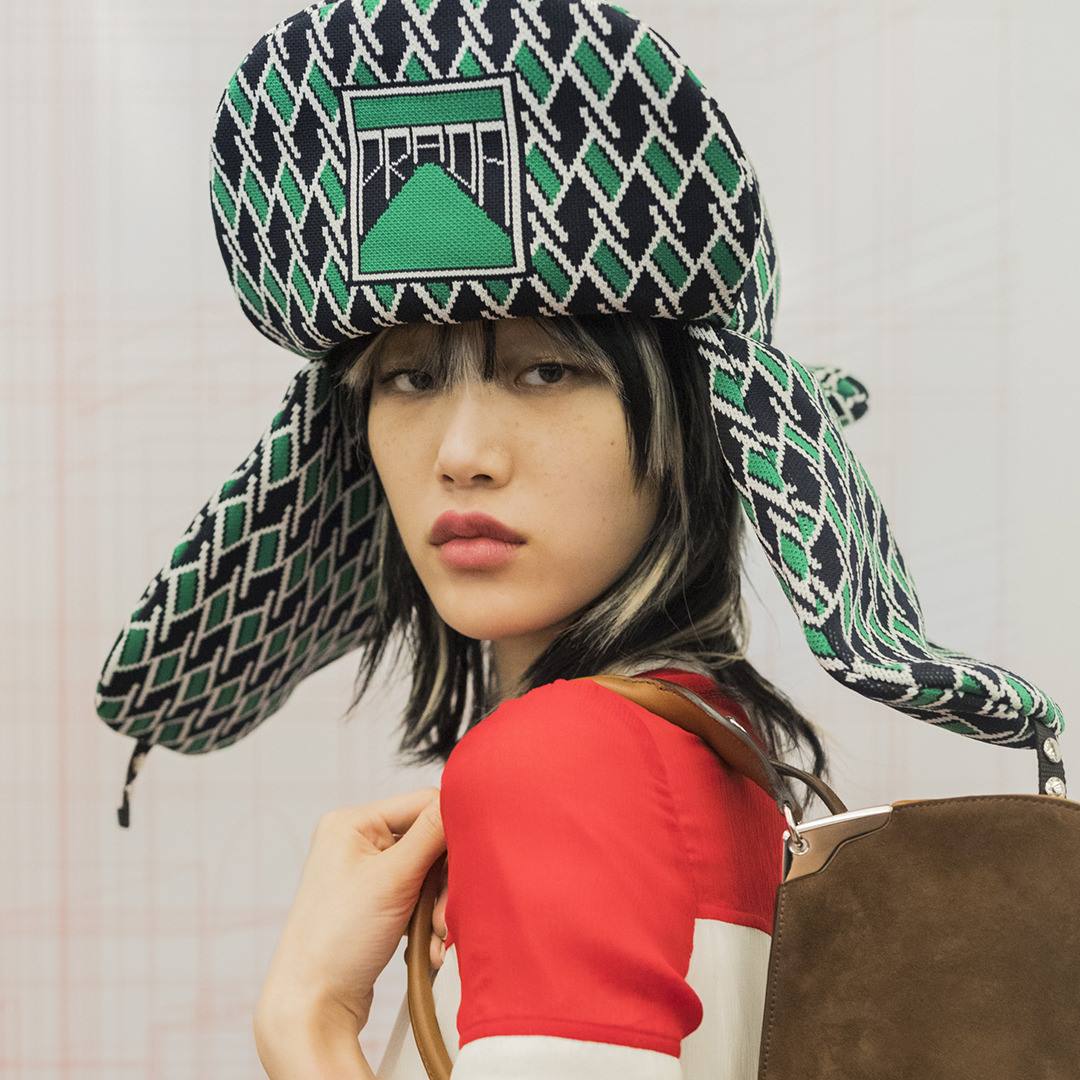 Prada - Sora Choi wears a jacquard hat with inset logo, partial