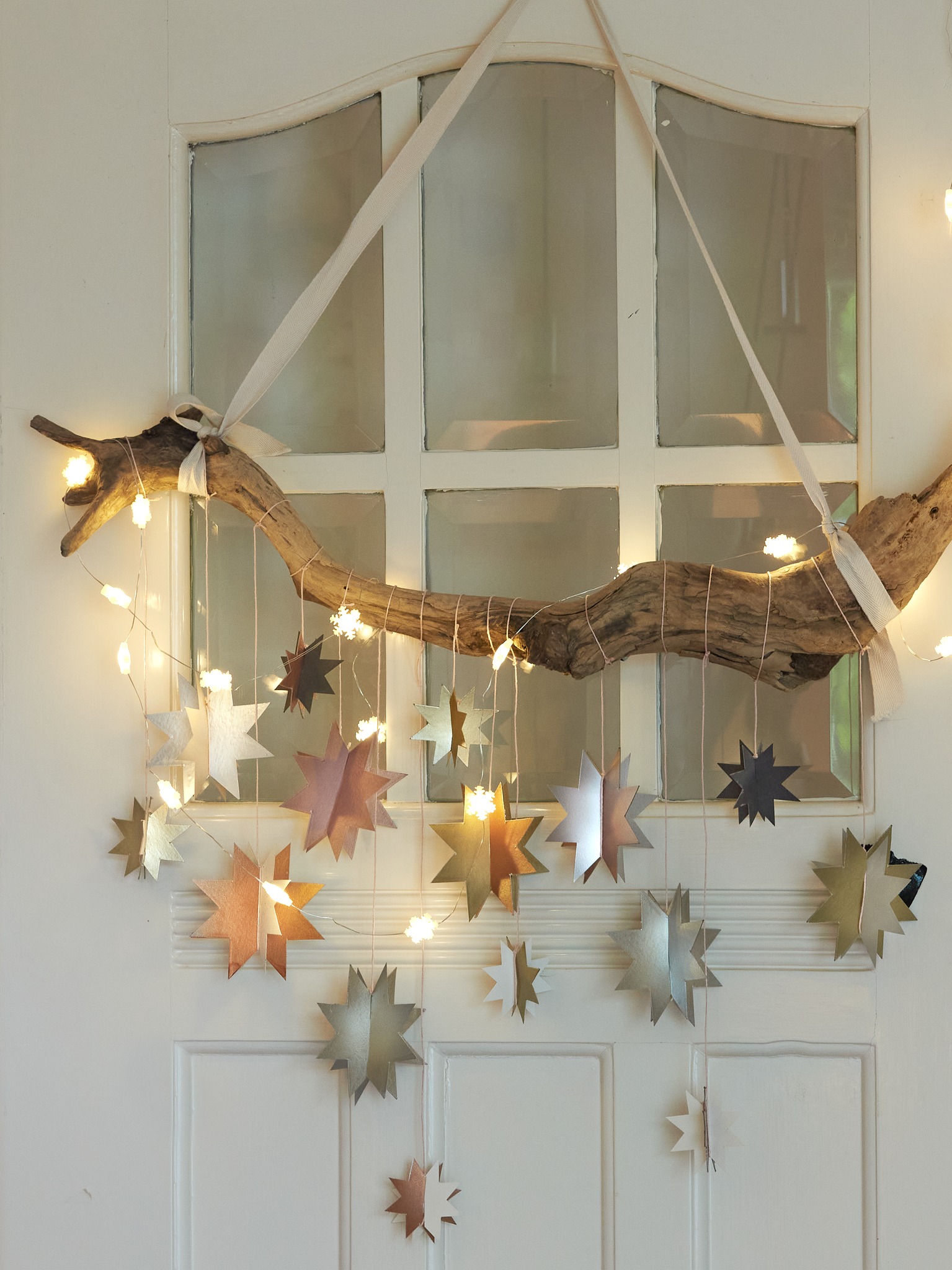 Ein Deko-Ast, geschmückt mit Papiersternen in glänzenden Metallictönen, sorgt im Nu für festliche Stimmung. Die Sterne werden mit dem Permanentspray (von edding.shop) besprüht und zusammen mit einer Lichterkette an einem dekorativen Ast