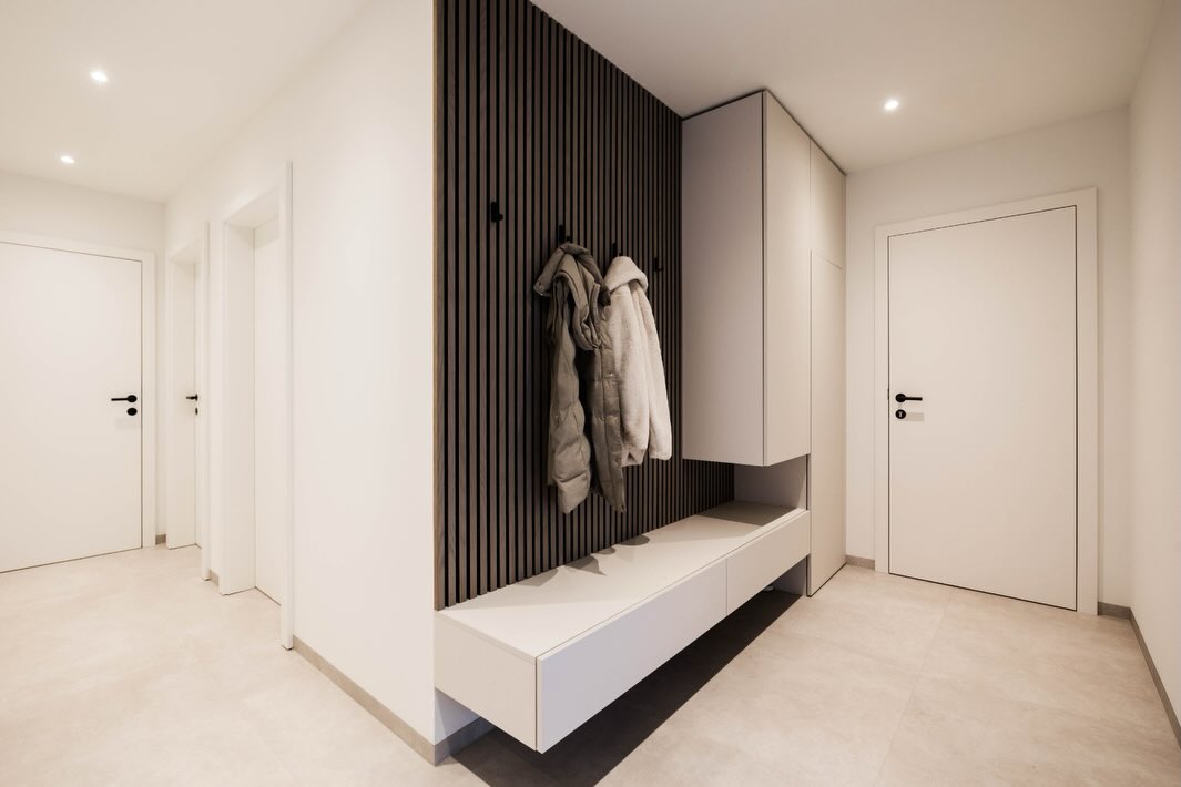 Ankommen und wohlfühlen. Diese stilvolle Garderobe präsentiert sich durch ihr reduziertes Design und eine klare Linienführung schlicht und modern. Ergänzt wird das Konzept durch maßgefertigte Stauraumschränke, die den gesamten Platz unter der