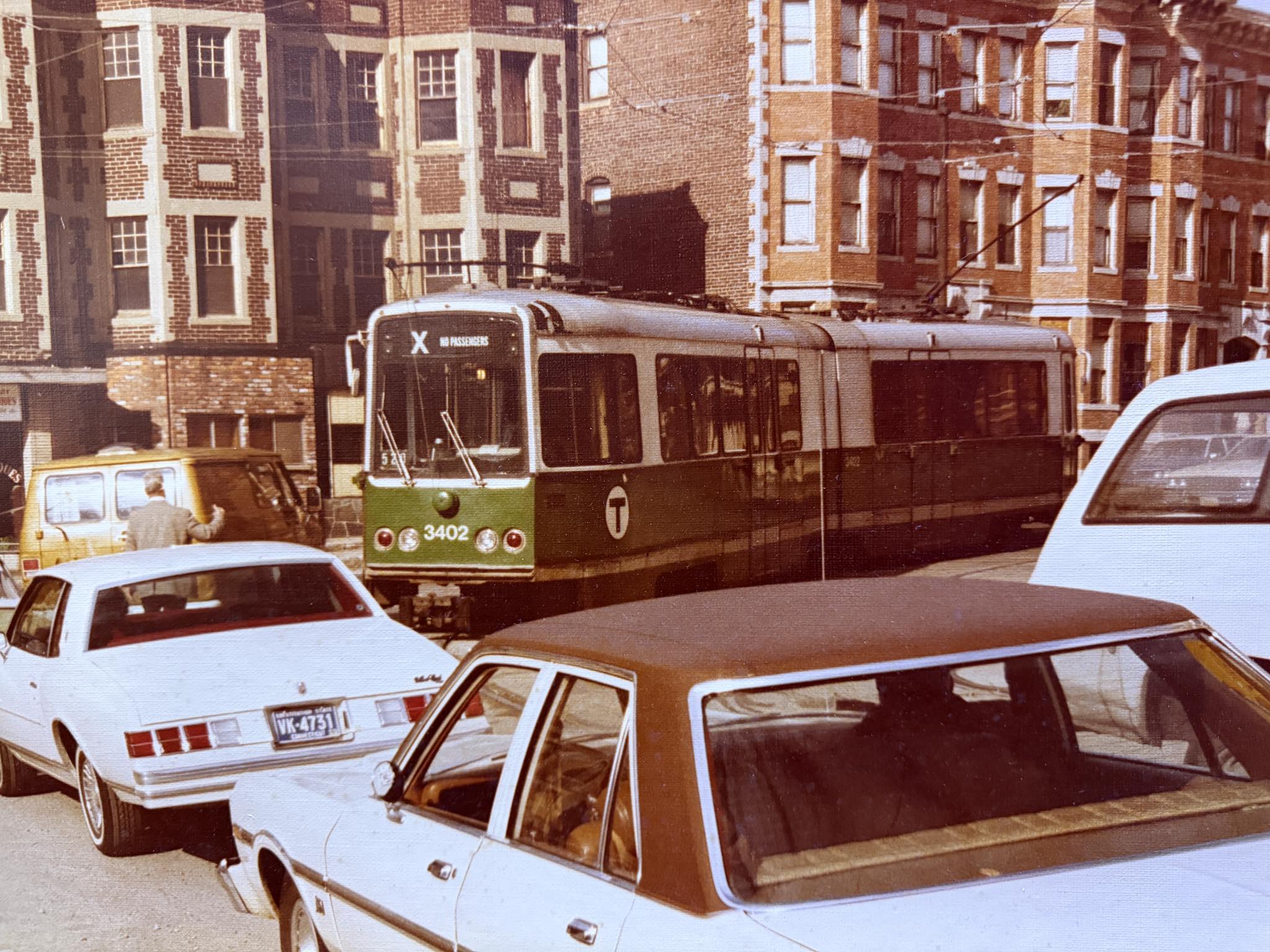 A vintage MBTA Green Line trolley moves through a Boston street 