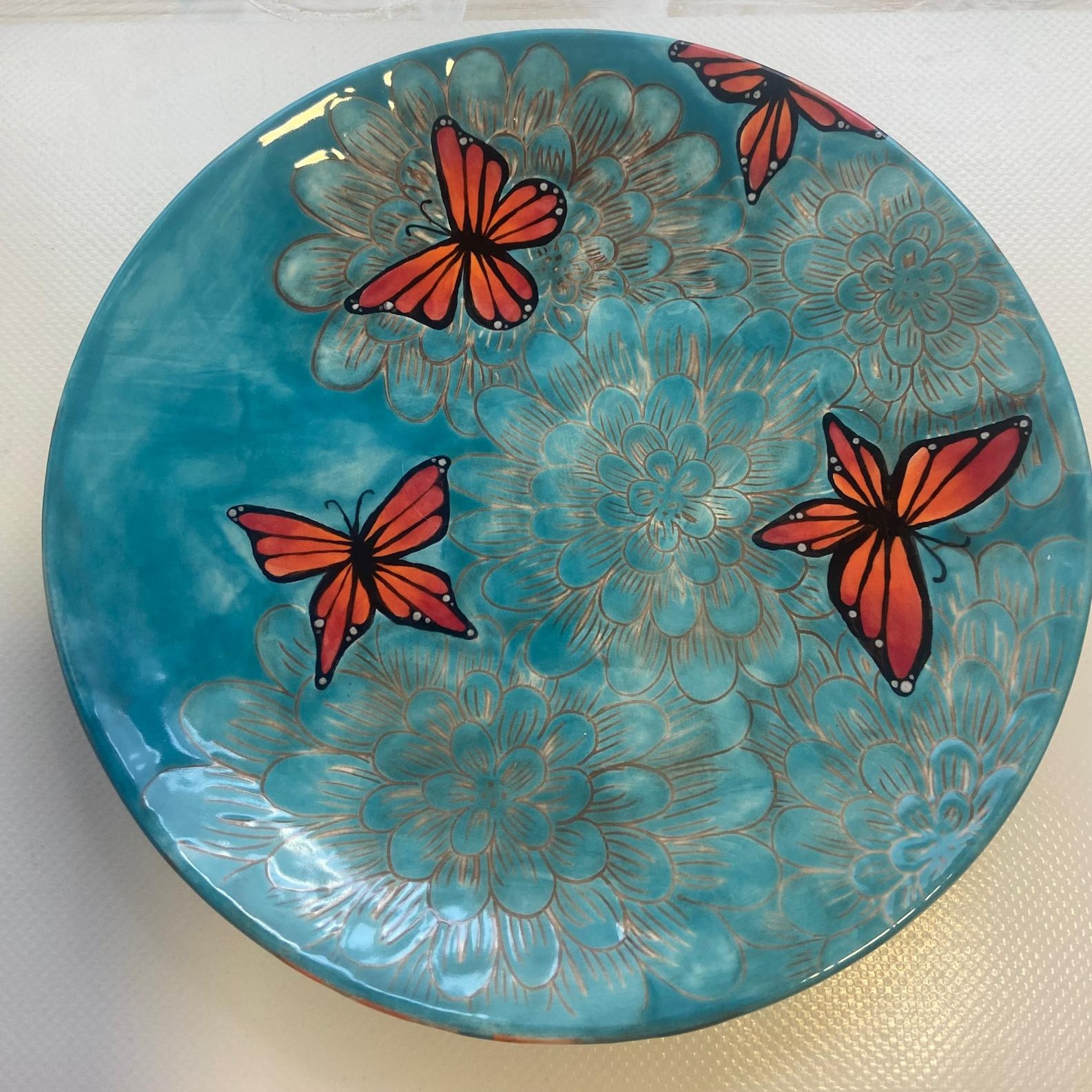 🦋✨ Ein Teller wie ein kleiner Sommertag Dieser handbemalte Teller vereint leuchtende Farben und feine Details. Die zarten Blütenmuster im Hintergrund und die kräftigen orangefarbenen Schmetterlinge lassen den Teller lebendig wirken –