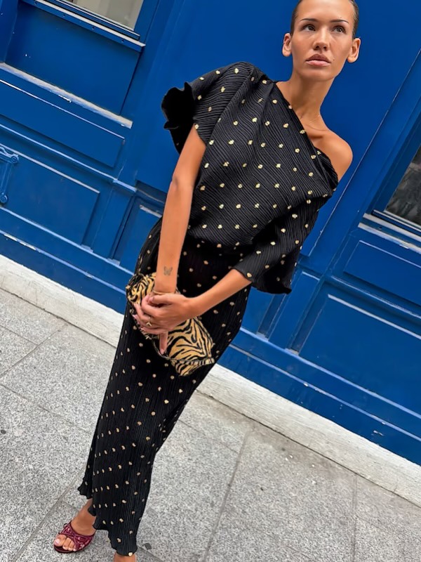 🌟🌟RE-STOCK🌟🌟 Here it comes again the iconic black Tilly with gold spots… Shimmering gold flecks set against a classic black plissé base. Cut with an asymmetric one-shoulder neckline, draped sleeve and an