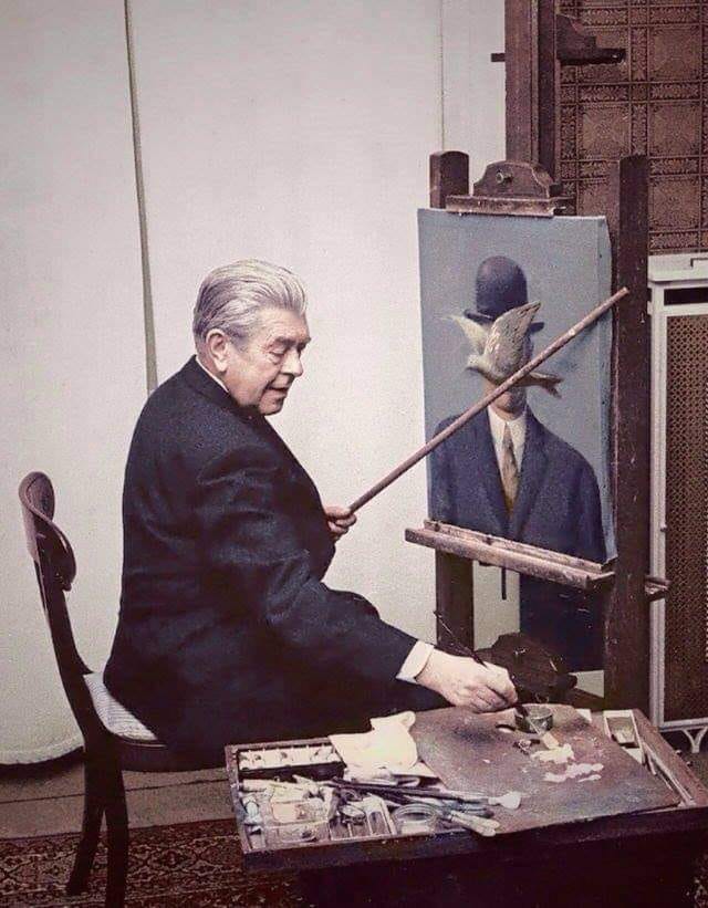 René Magritte at work in his living room, 1964. The suit and the