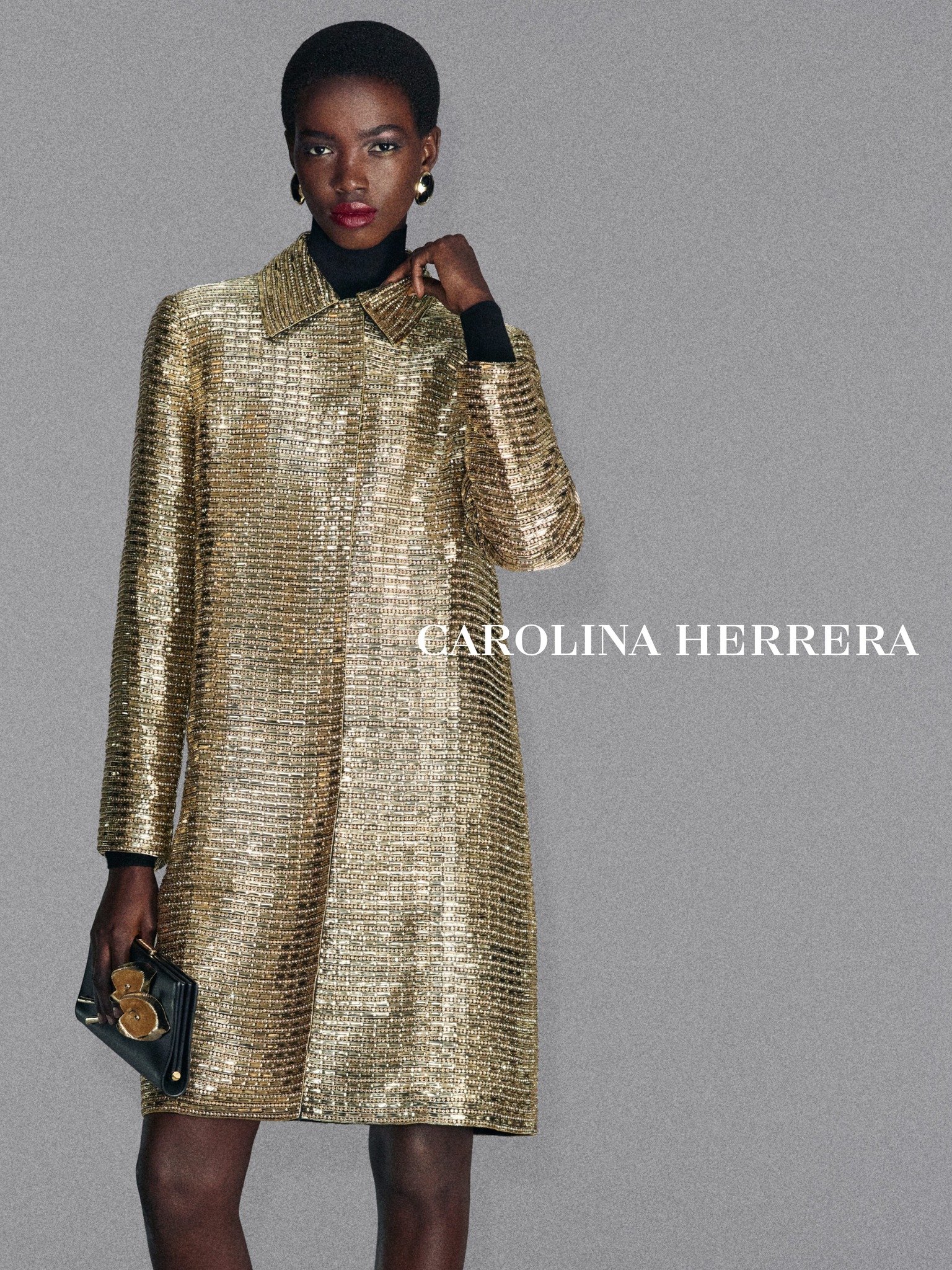 Introducing the Carolina Herrera Fall 26. Fama wears a gold coat hand-embroidered with baguette sequins, glass bugle beads, and crystals, paired with a black leather clutch featuring calla lily details. Discover the