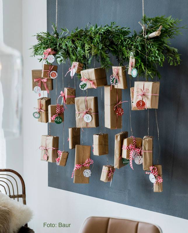 Hübsche Idee für einen Adventskalender: Tannengrün mit Blumendraht um einen Ast arrangieren, diesen an die Decke hängen und mit kleinen Adventspäckchen bestücken. Eine genaue Anleitung und die hübschen Zahlenanhänger zum Ausdrucken gibt