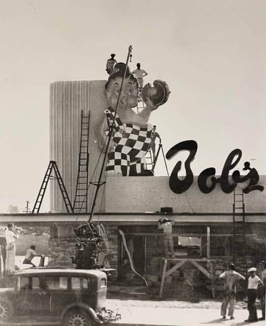 Workmen with wooden ladders and a vintage crane are pictured here