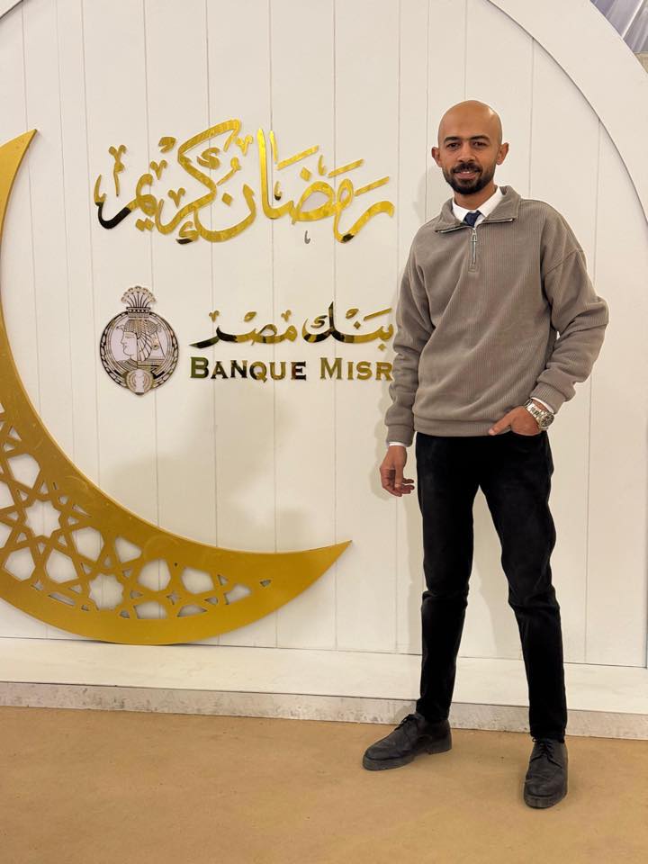 Mostafa - Man standing confidently in front of a white Instagram-themed ...