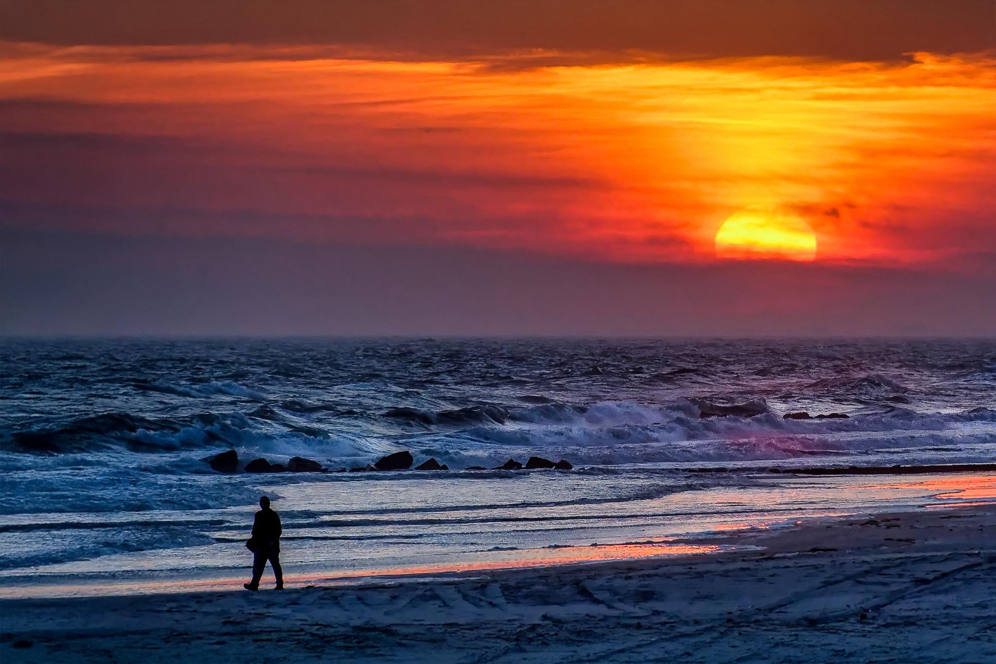 Man spotted beyond the water at Wildwood beach sunset