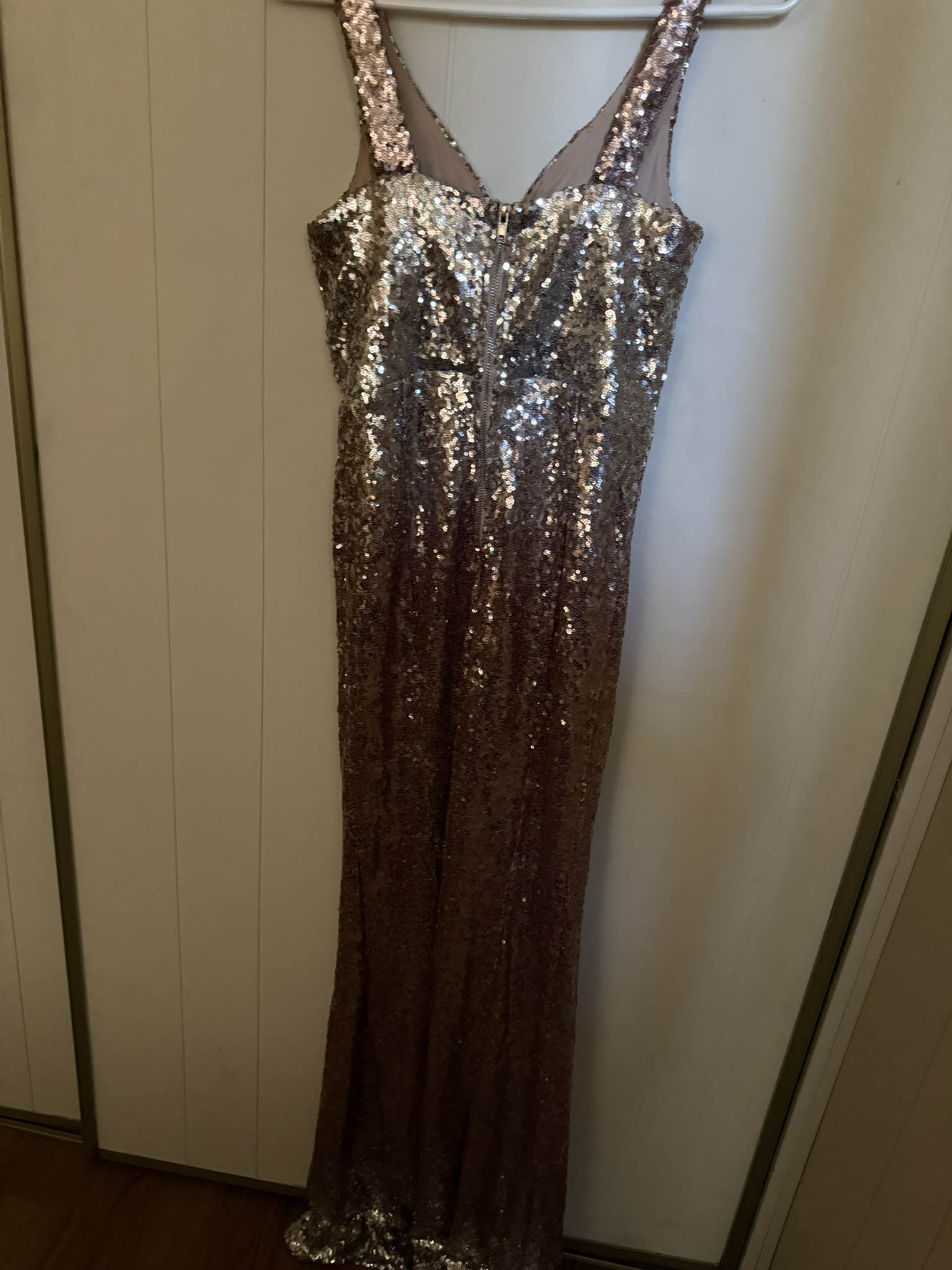 Stunning rose gold sequin gown is a size 3. This floor-length dress from Crystal Doll is covered in shimmering sequins and has a V-neckline with a zipper closure at the back. The
