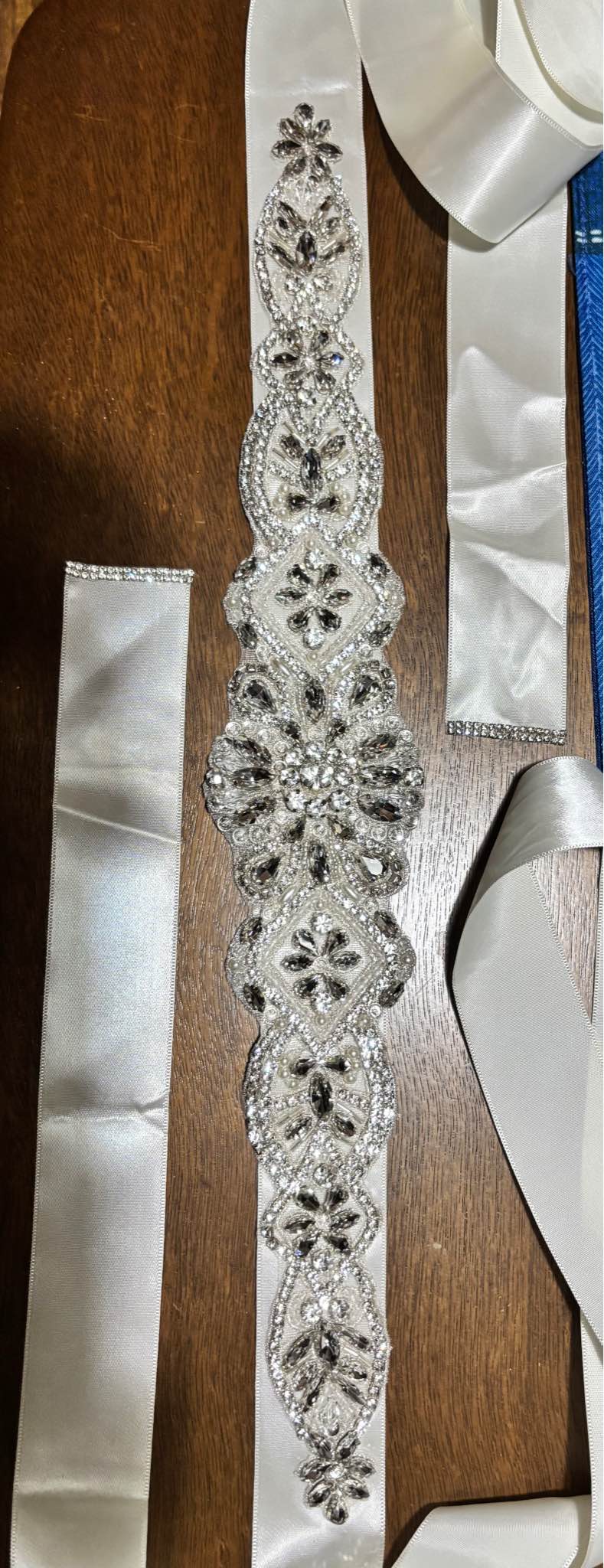 wedding dress belts ivory Elegant rhinestone bridal belt with an satin ribbon. This sash has a large central floral crystal motif and smaller repeating rhinestone patterns along the length. The ribbon ends are finished with bridal sash belt