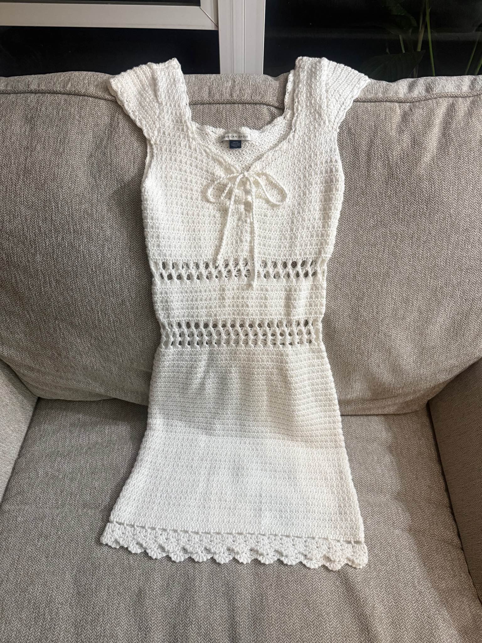 Beautiful white crocheting tmini dress from American Eagle. This size small dress has a tie-front neckline, cap sleeves, and open-knit detailing at the waist and hem